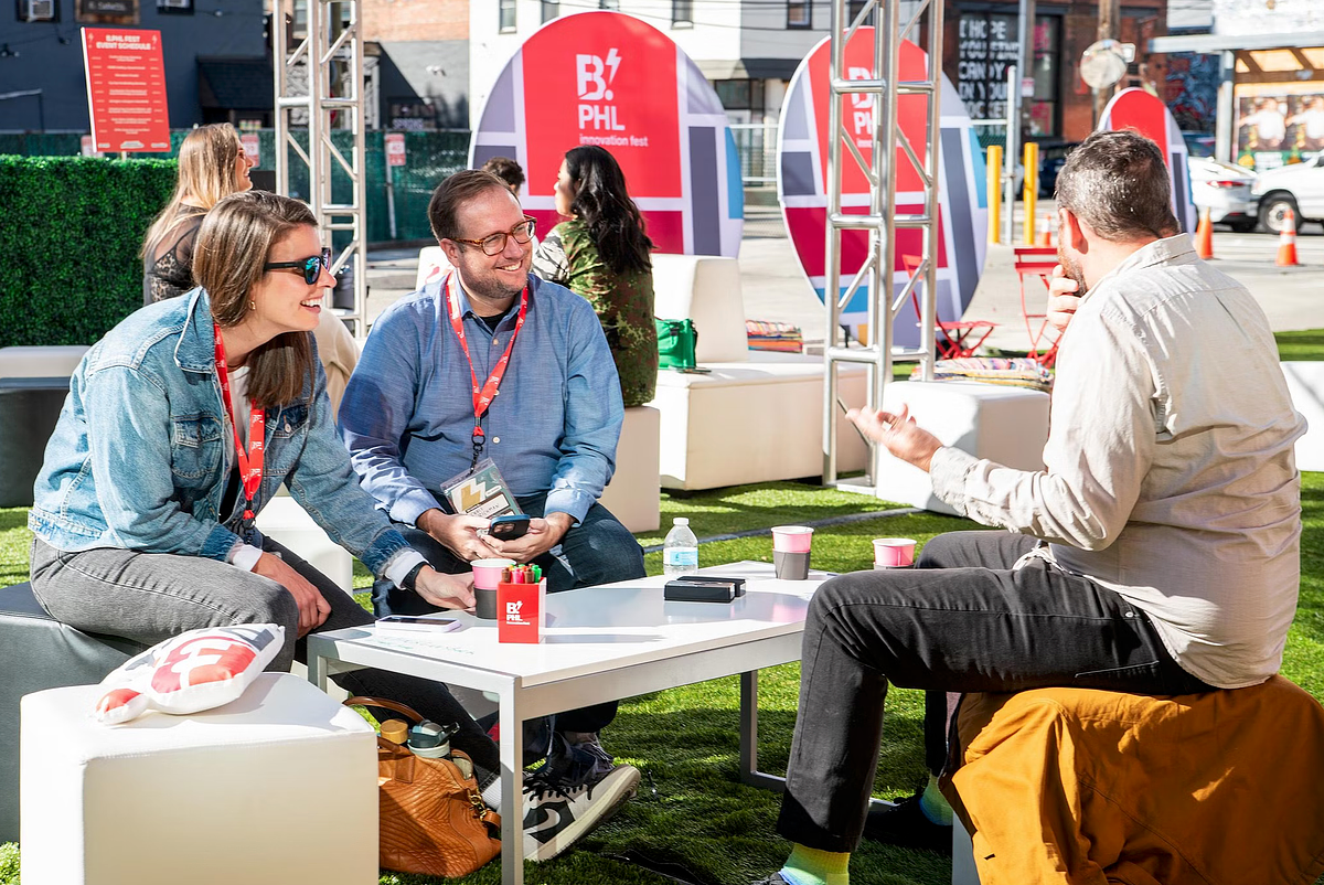 Attendees networking and sharing ideas over coffee in the outdoor Innovation Lounge at B.PHL Fest 2023 in Philadelphia, captured by professional event photographer.