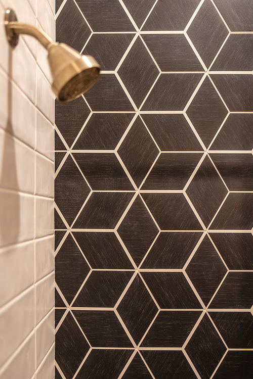 Geometric wall tile, satin brass shower fixtures in son's bathroom
