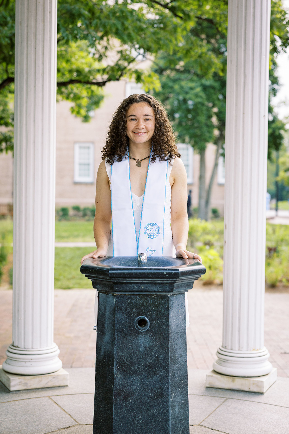 A UNC Chapel Hill senior standing at the Old Well on UNC's campus