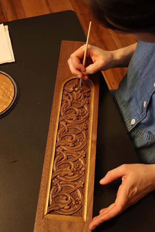 Kelly Baker paints fine details on the stem panel by hand