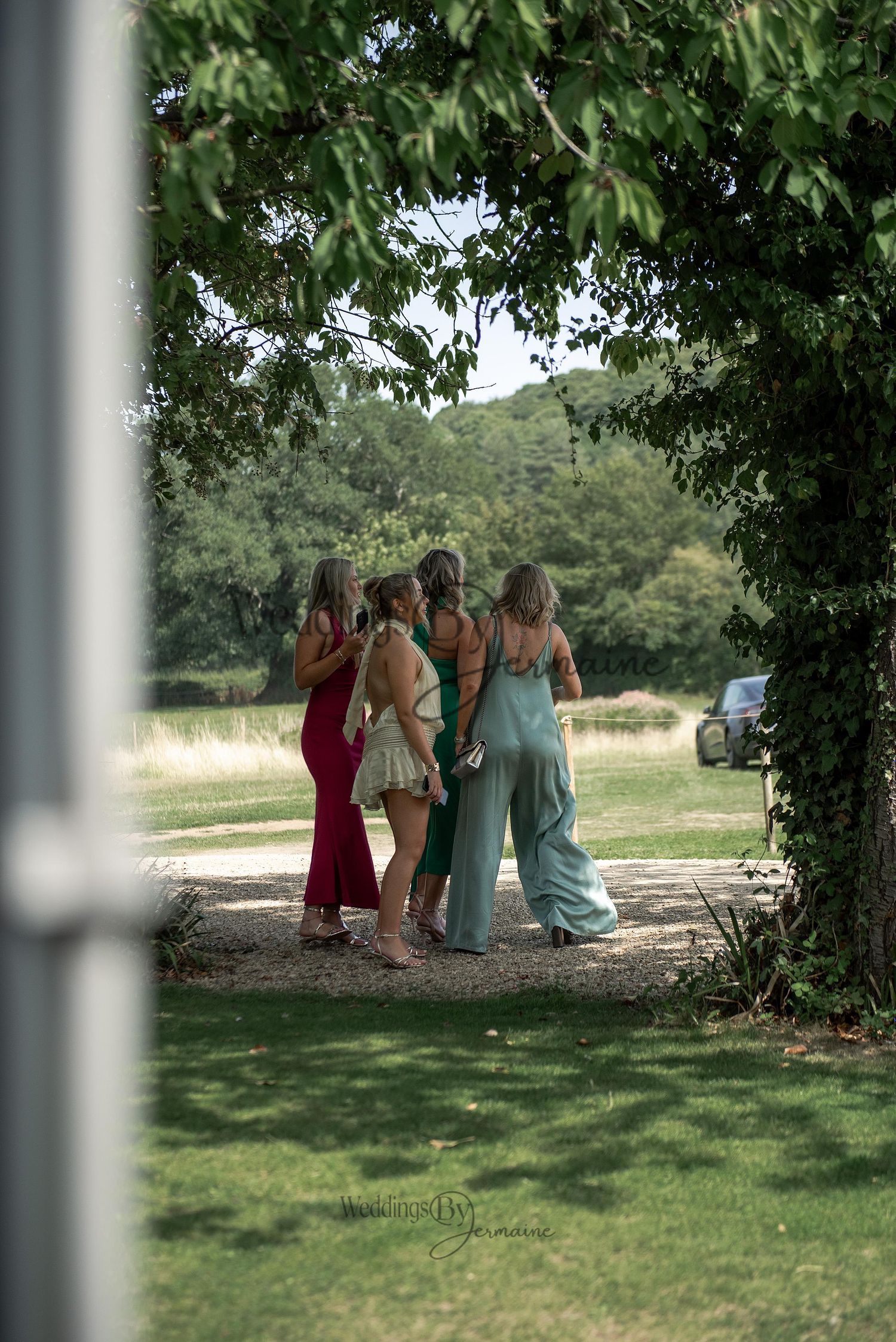 Group of four women with their backs turned, candidly captured on wedding grounds by Weddings by Jermaine