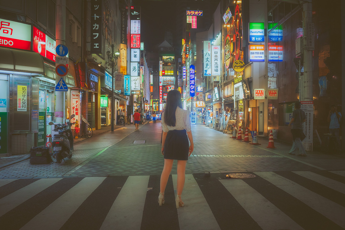 Rue d'Ikebukuro la nuit, une passante se retourne devant les néons