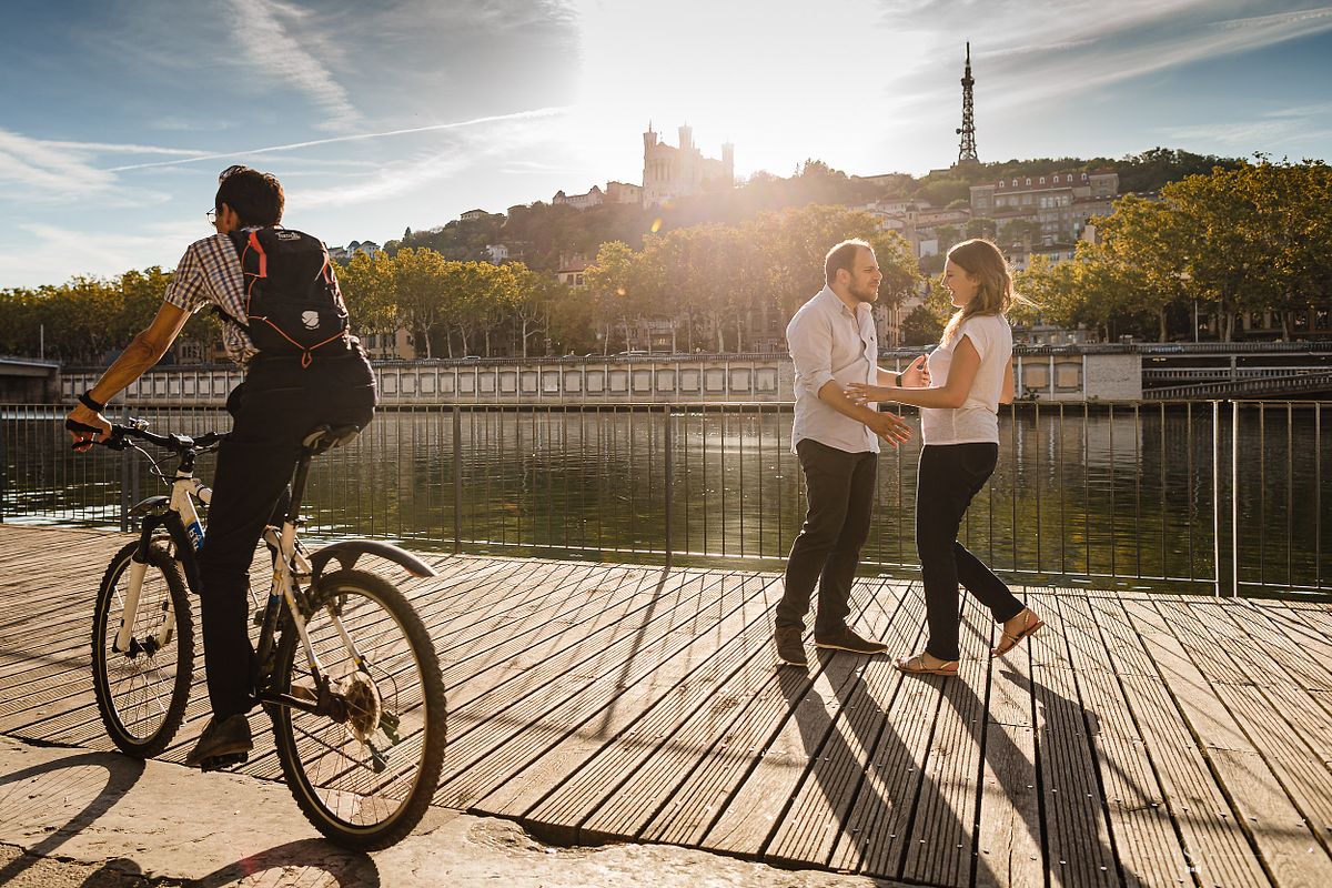 Tarif Photographe Mariage - Sebastien CLAVEL Photographe - Couple dansant sur un quai &agrave; Lyon, v&eacute;lo au premier plan et basilique en fond, un coucher de soleil en douceur