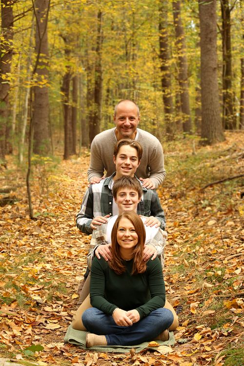 Family of four posing in the woods, stacked