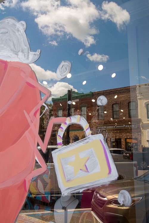 Painted shrimp holding a purse on a store window for the Isle of Eight Flags Shrimp Festival, with historic downtown Main Street in the background