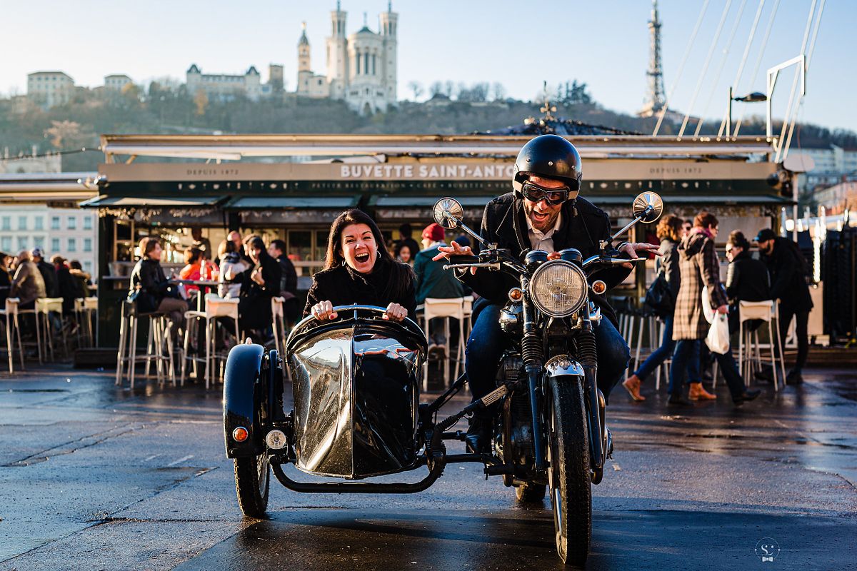 Tarif Photographe Mariage - Sebastien CLAVEL Photographe - Couple riant sur une moto avec side-car devant la buvette Saint-Antoine, avec la Basilique Notre-Dame de Fourvi&egrave;re en arri&egrave;re-plan