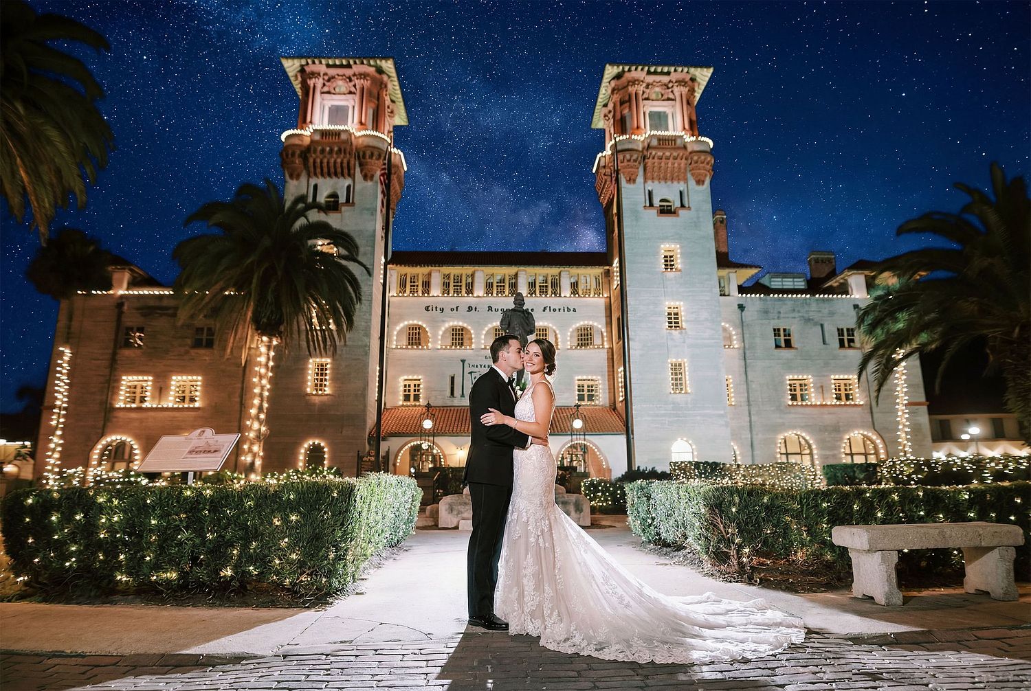 Luxury wedding photography in North and Mid Florida featuring a bride and groom kissing in front of a historic illuminated estate under a starry night sky.