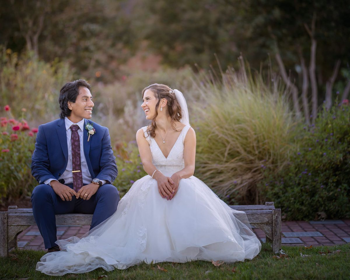 bride and groom sitting on a stone bench on a grey overcast day