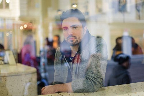 Toni Gojanovi? sitting in a bar with a reflection on the glas.