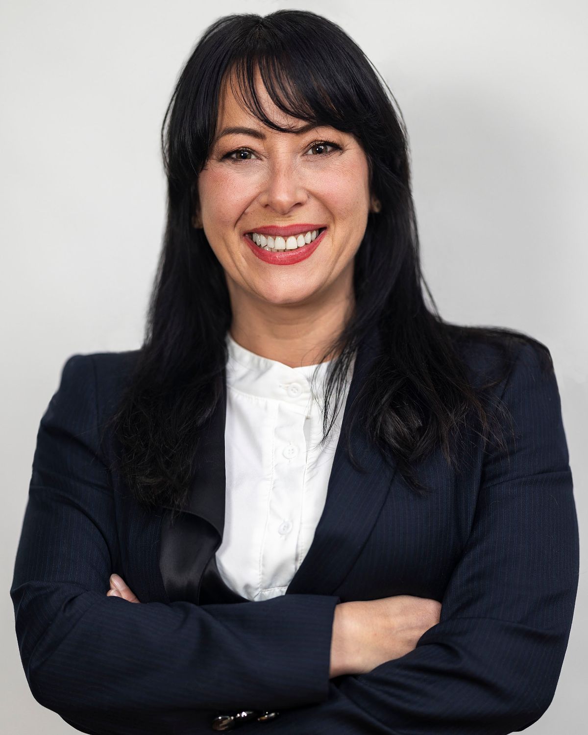 Corporate portrait of a female business woman wearing a black suit and white shirt against a white background.
