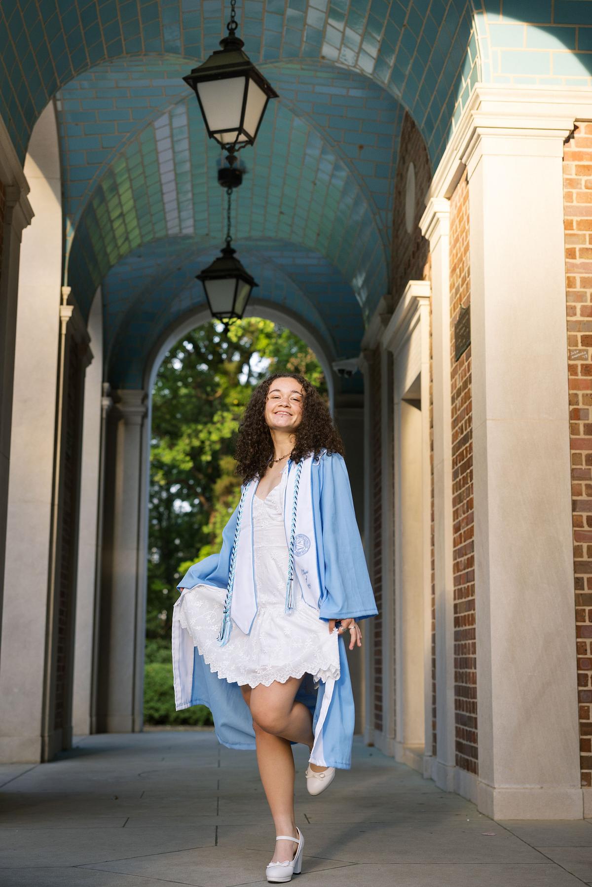 A woman in her graduation robe and stole at the Bell Tower on UNC's campus in Chapel Hill, NC