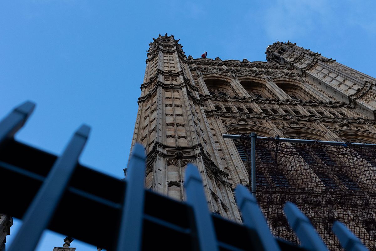 Upp&aring;tvinkel av gotisk byggnadsfasad i Westminster, London, med staket i f&ouml;rgrund och bl&aring; himmel.