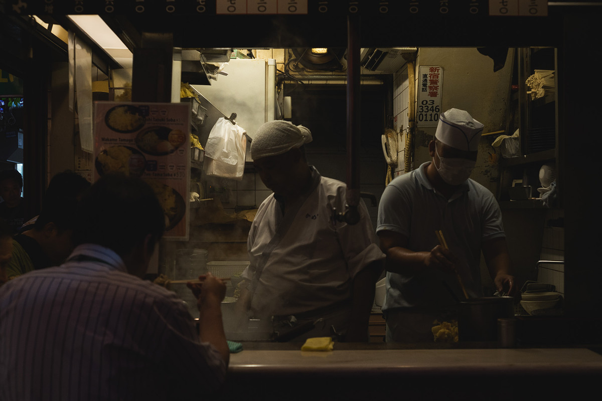 Cuisiniers en action derrière le comptoir d'un yakitori d'Omoide Yokocho