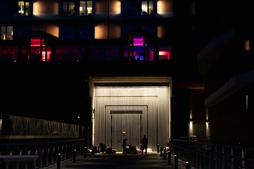 People gathered under illuminated structure at night in Stockholm, colorful background lights