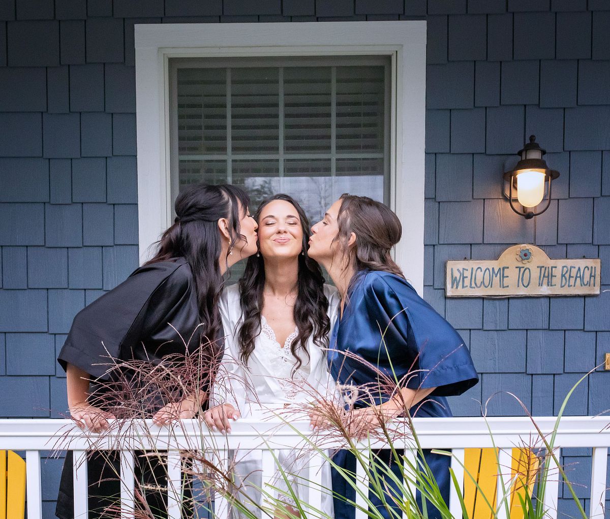 bridesmaids kissing the bride on the porch in Selbyville, DE before getting dresses