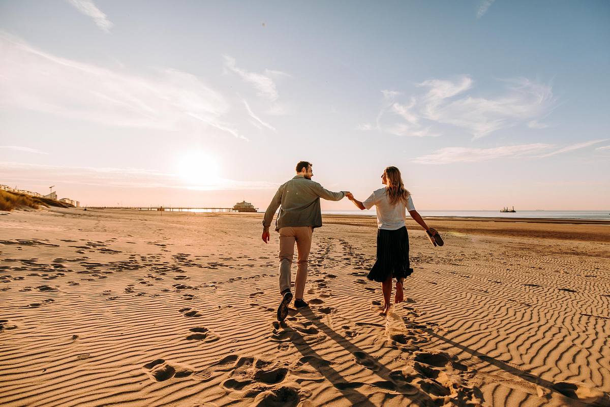 Hand in hand wandelen op het strand tijdens een verlovingsshoot