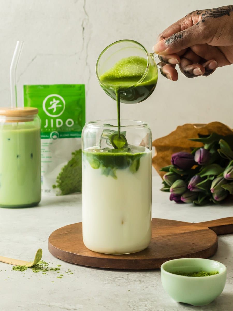 Pouring matcha into a cup of milk