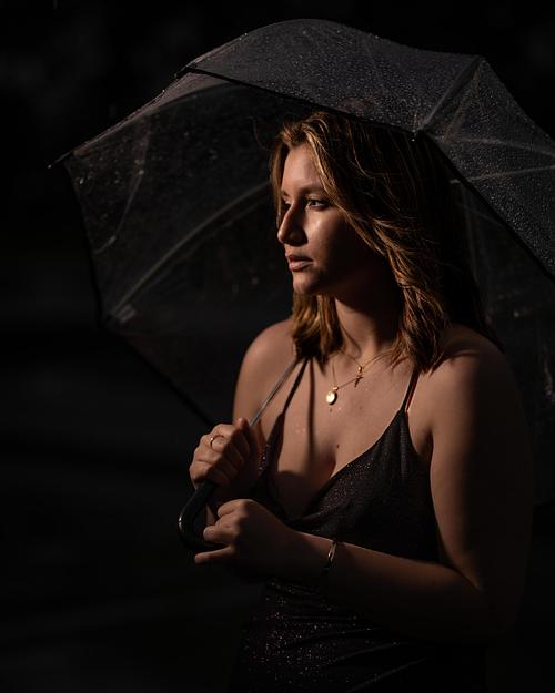 Edmonton High School Grad standing under an umbrella in the rain.