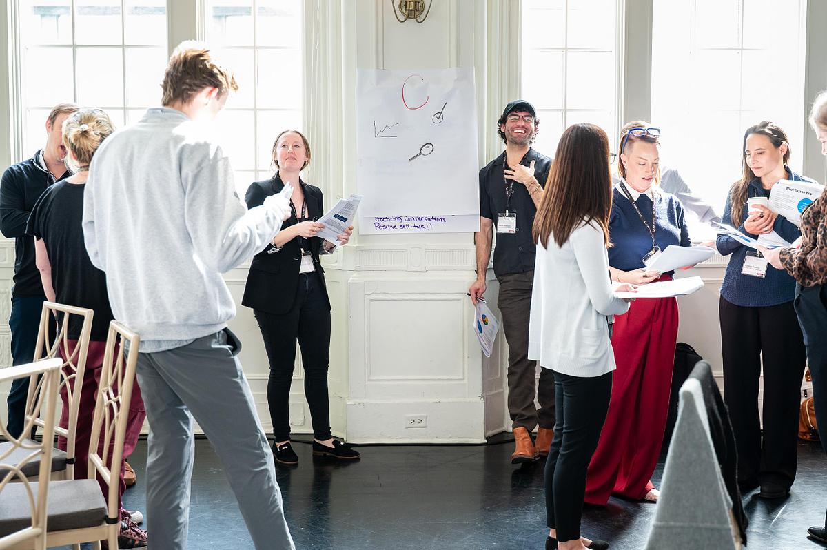 Professionals participating in a workshop session in the Bellevue Rose Garden Room in Philadelphia, gathered around a presentation board during a corporate event
