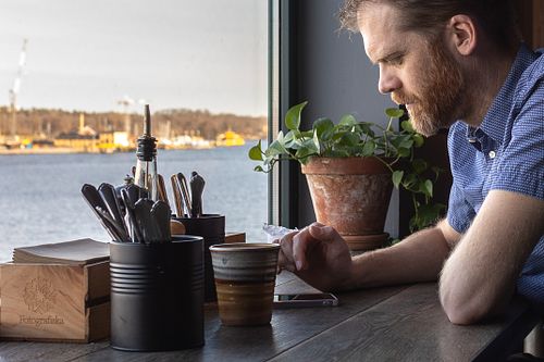 Man vid fönsterbord med kaffe och utsikt över vattnet på Fotografiska