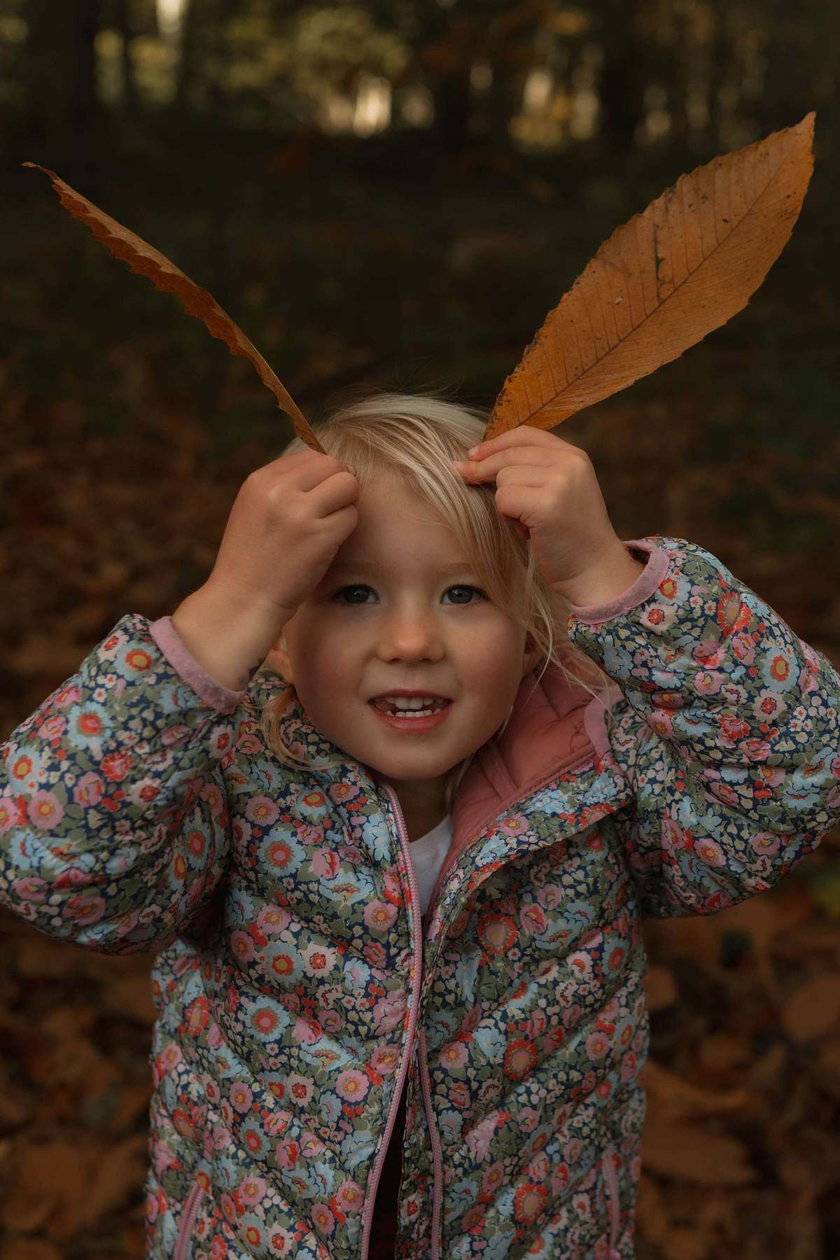 Young girl holding large autumn leaf outdoors, children's lifestyle photography Northamptonshire