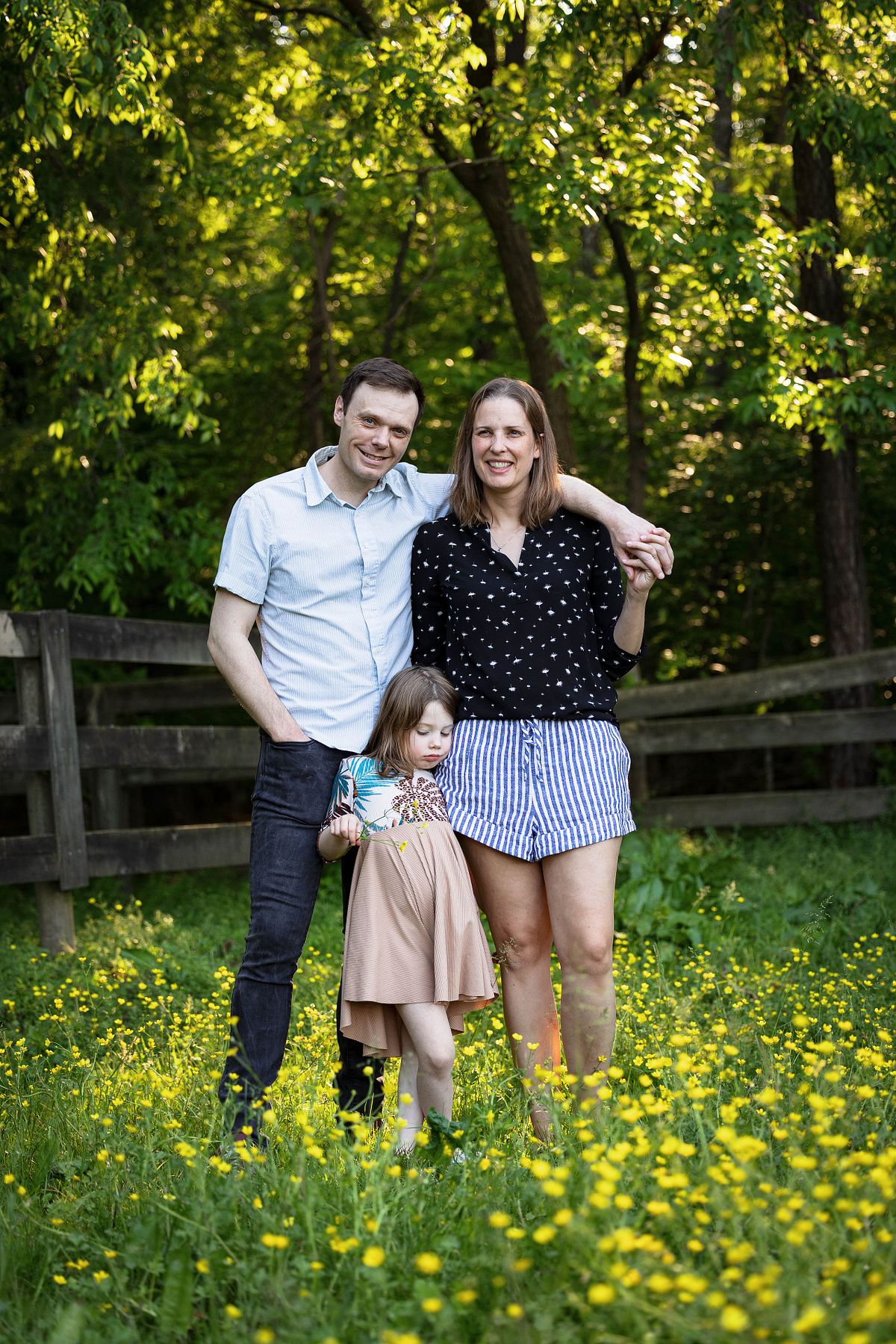 A father, mother, and daughter posing for a photograph in a field in the spring on a farm outside Chapel Hill, NC