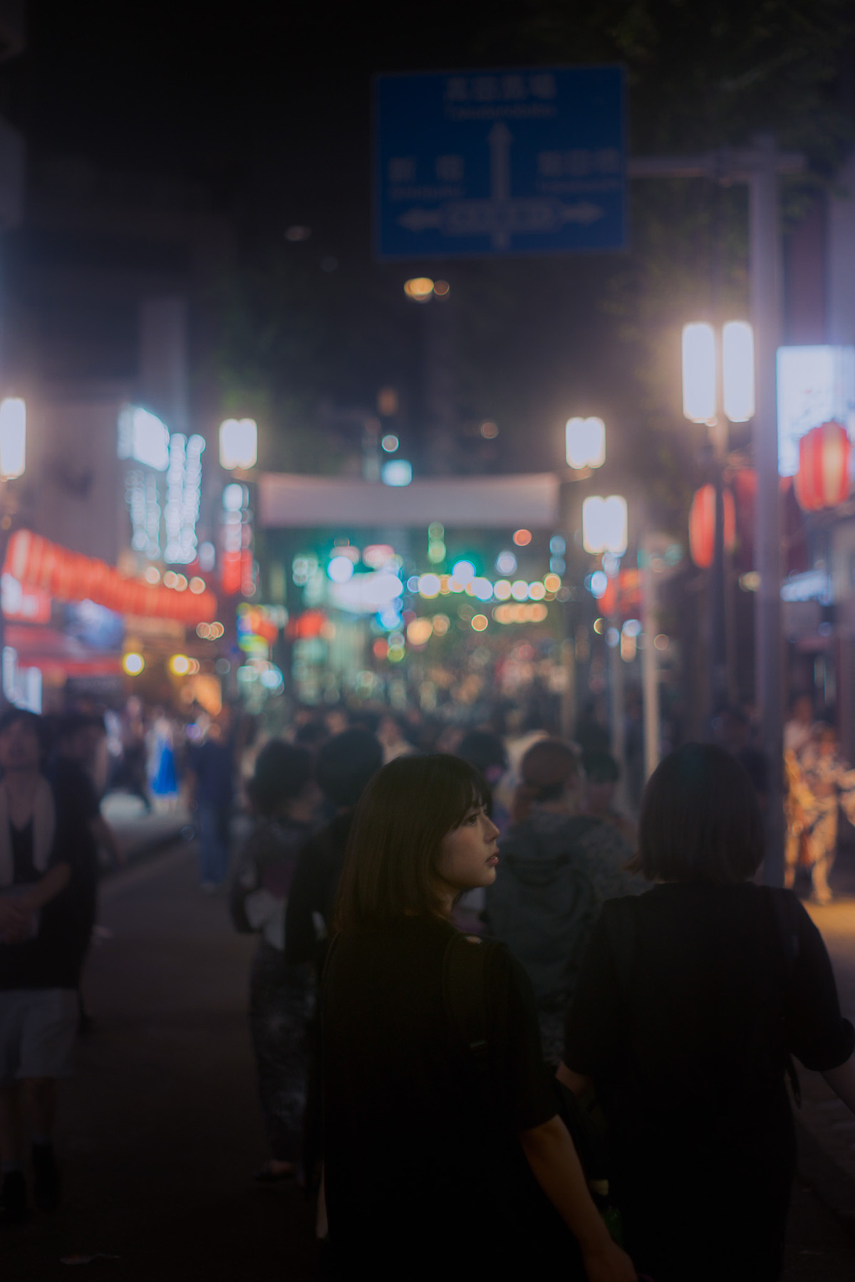 Foule de nuit dans une rue de Tokyo, néons en bokeh derrière les passants