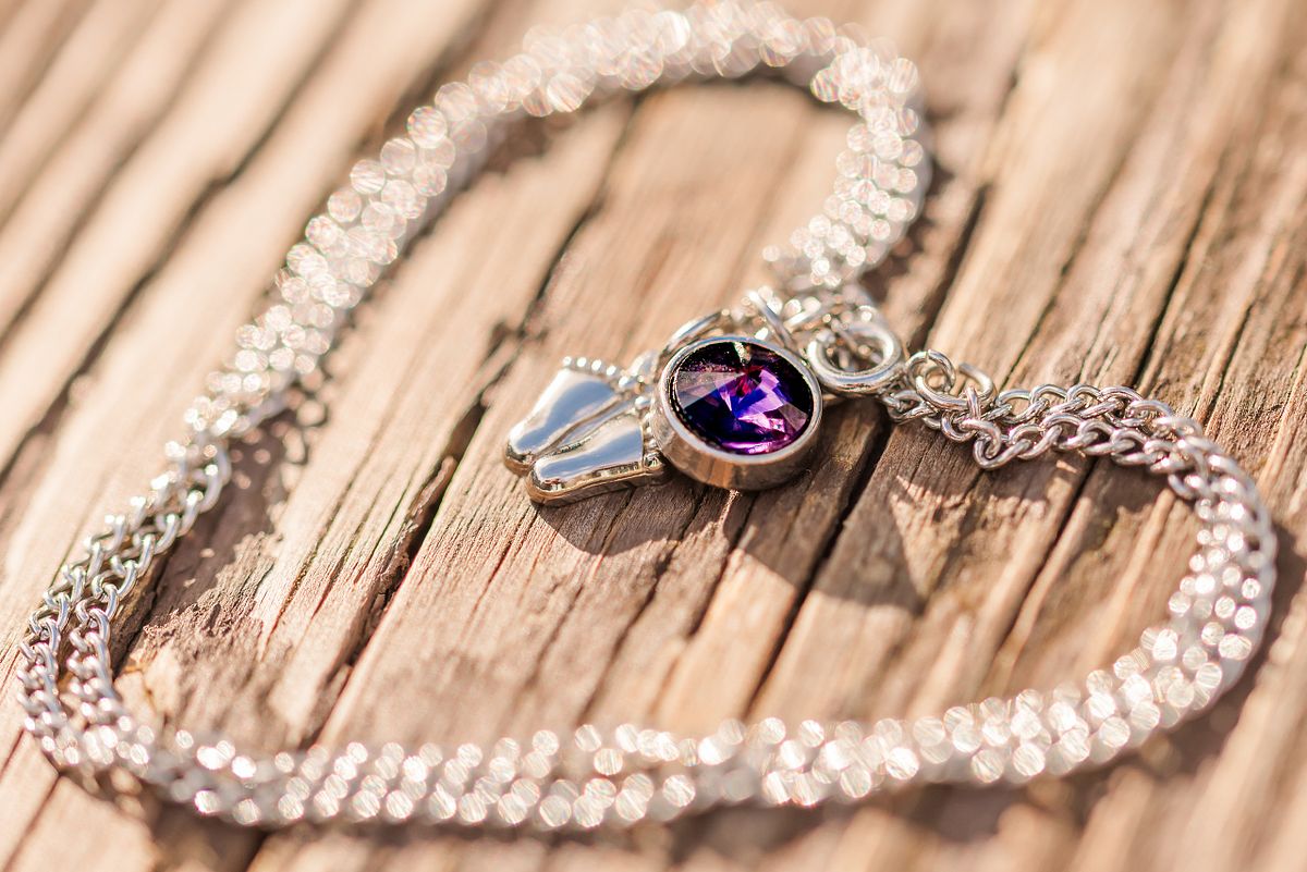 Necklace with tiny baby feet and February birth stone