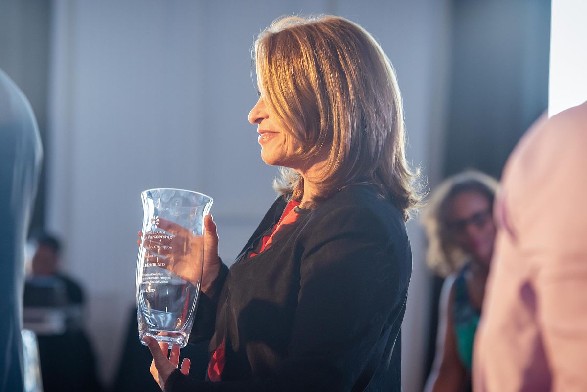 Corporate event photography capturing a woman holding a glass award during a recognition ceremony in Philadelphia, highlighting leadership, achievement, and professional excellence.