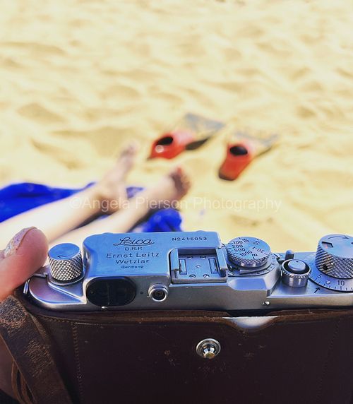 A Leica camera with a beach and flippers in the background