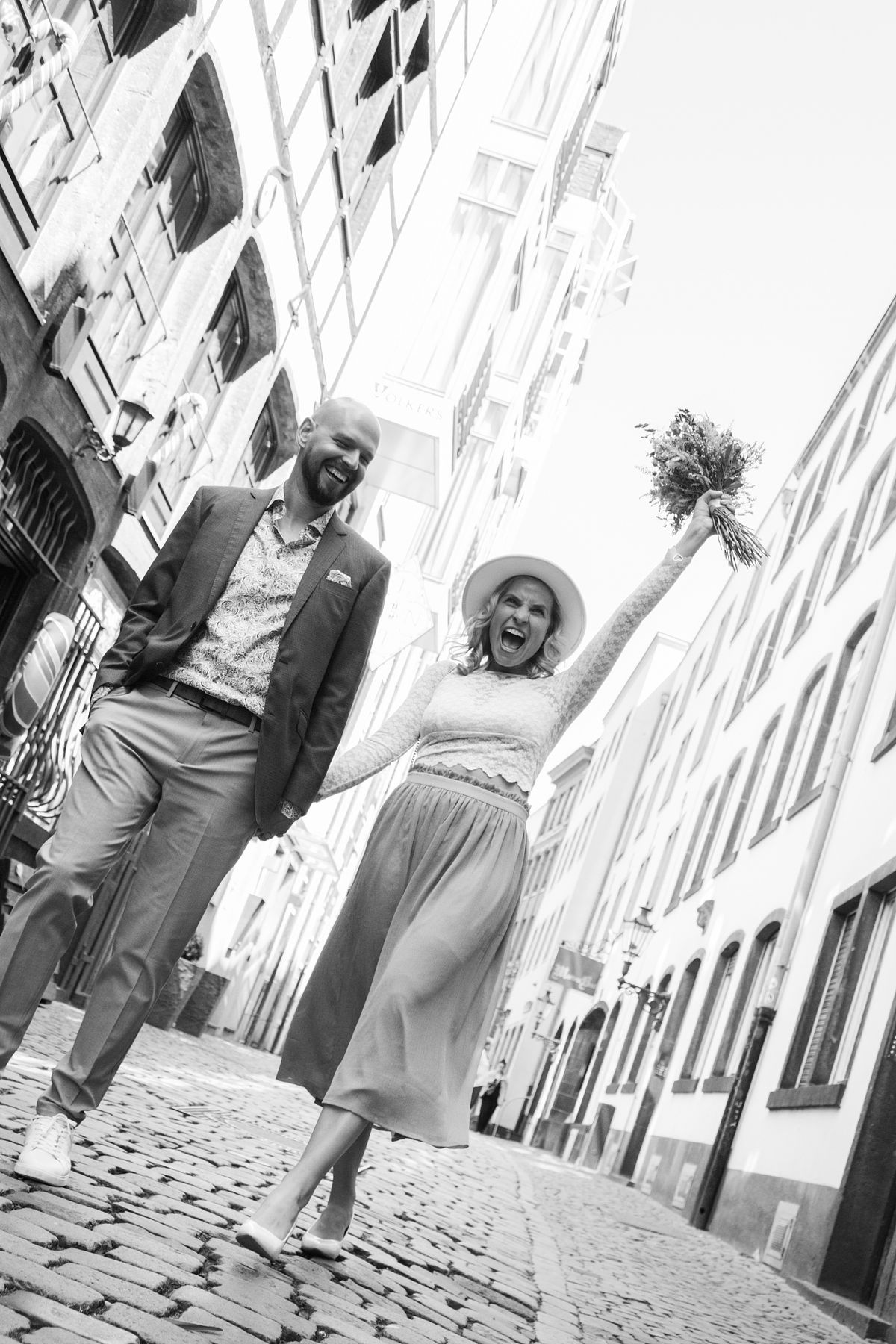 Brautpaar posiert w&auml;hrend des Shootings in der historischen K&ouml;lner Altstadt, urbane Hochzeitsfotografie mit Fokus auf Architektur.