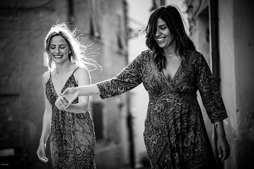 "coppia passeggia mano nella mano sorridente per le strade di Alghero"