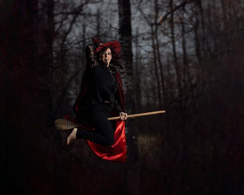 A witch flies through the forest on her broomstick.