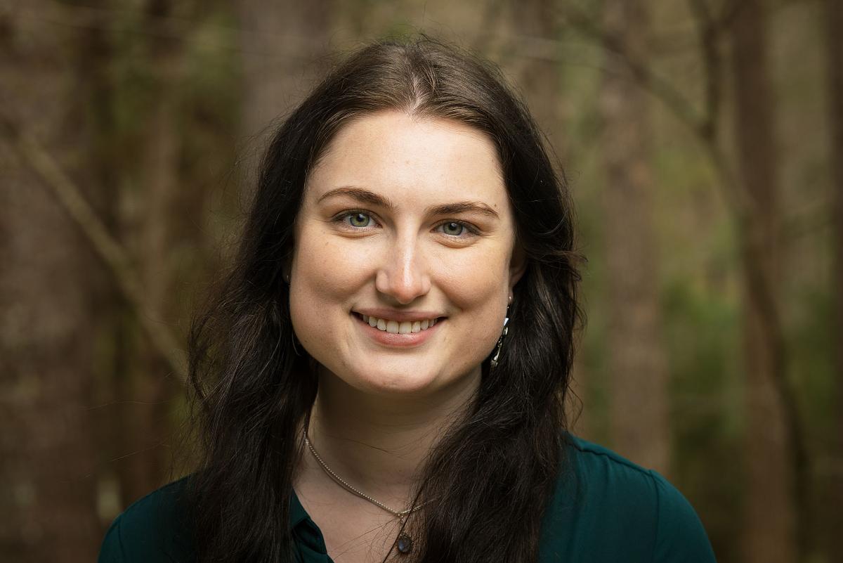 A woman posing for a headshot with a wooded background in Chapel Hill, NC