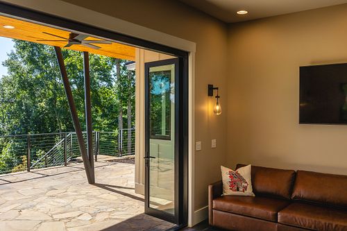 Leather couch; wall sconce, Open bifold glass door; looking to the angled steel posts that come together at a single point load