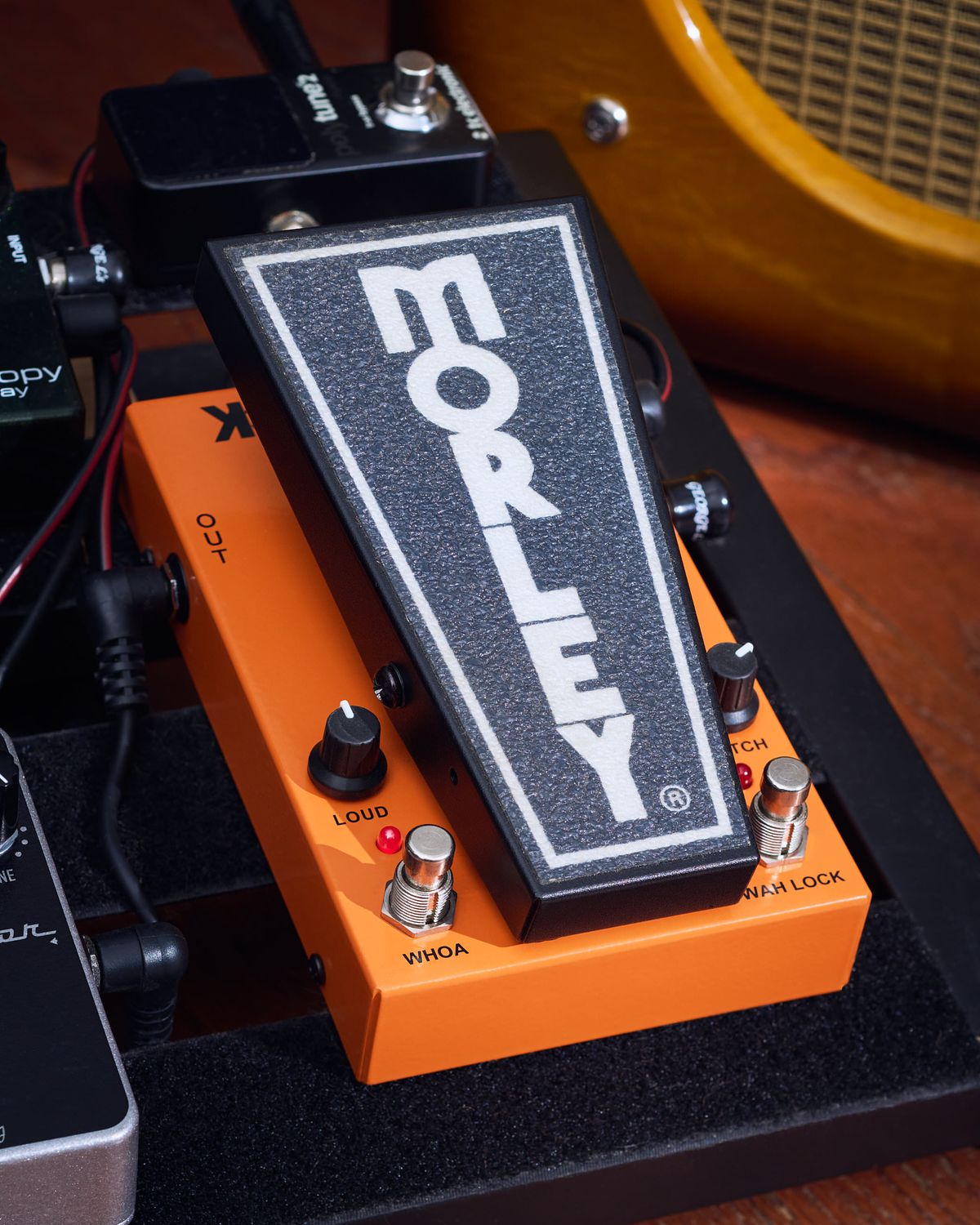 Orange and black wah pedal mounted on a pedalboard.