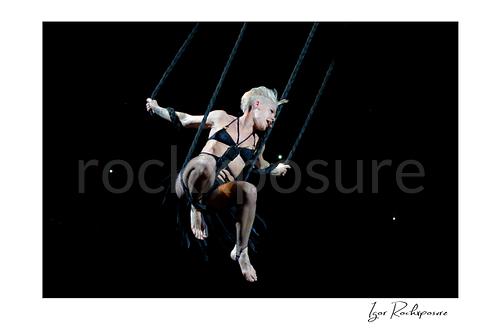 Horizontal color image of Pink suspended high above the stage on ropes during a dramatic live performance
