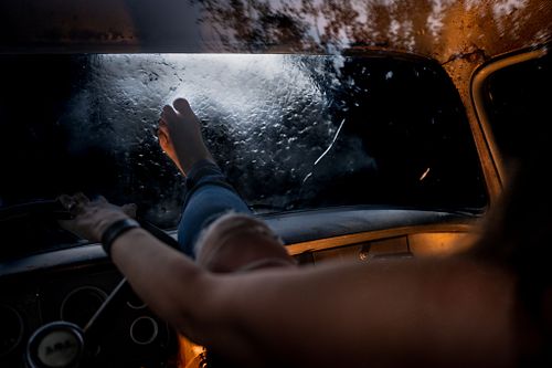 A woman trying to kick through a windshield as water rushes over the vehicle.