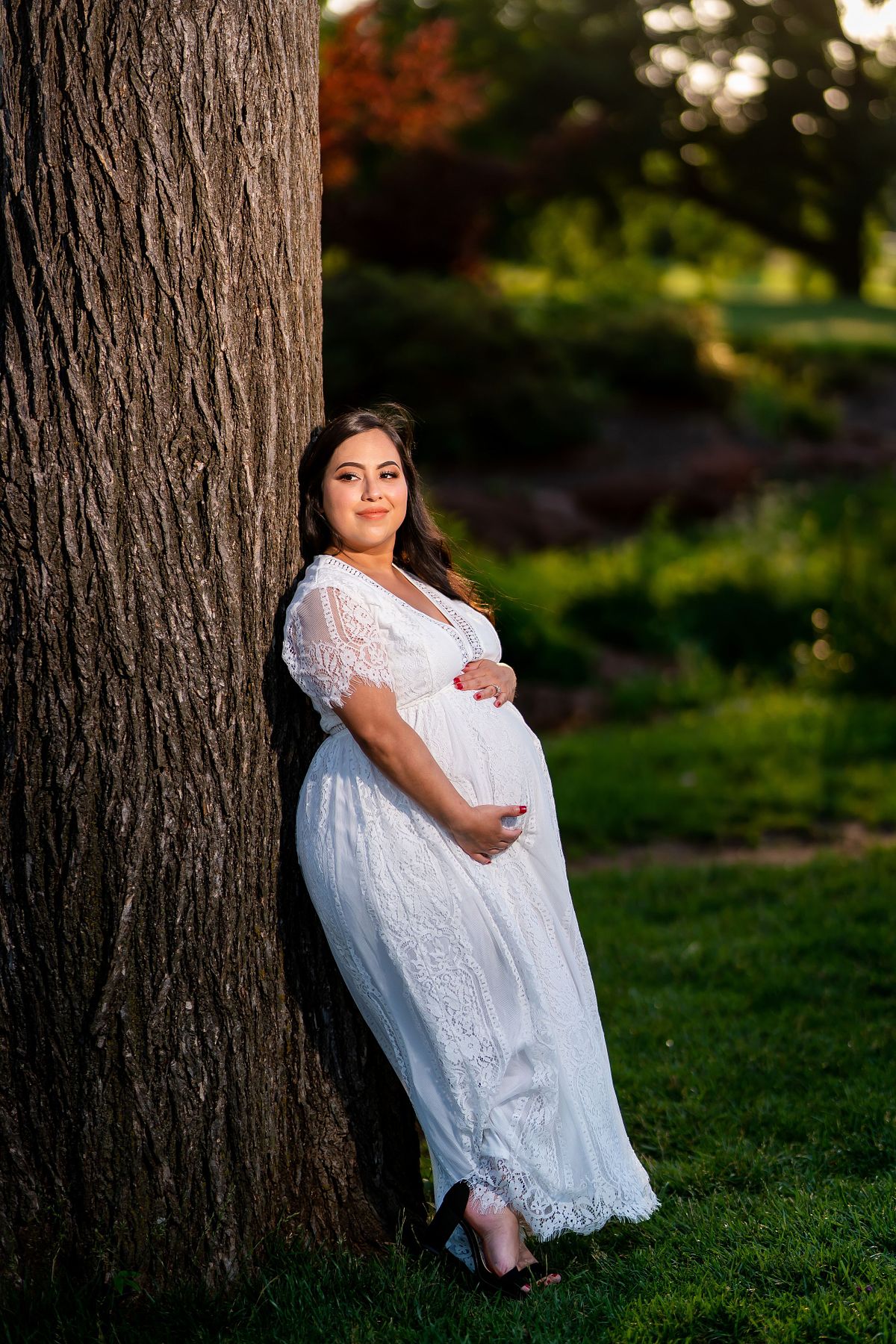 Pregnant woman posing in natural light with a flowing maternity gown.