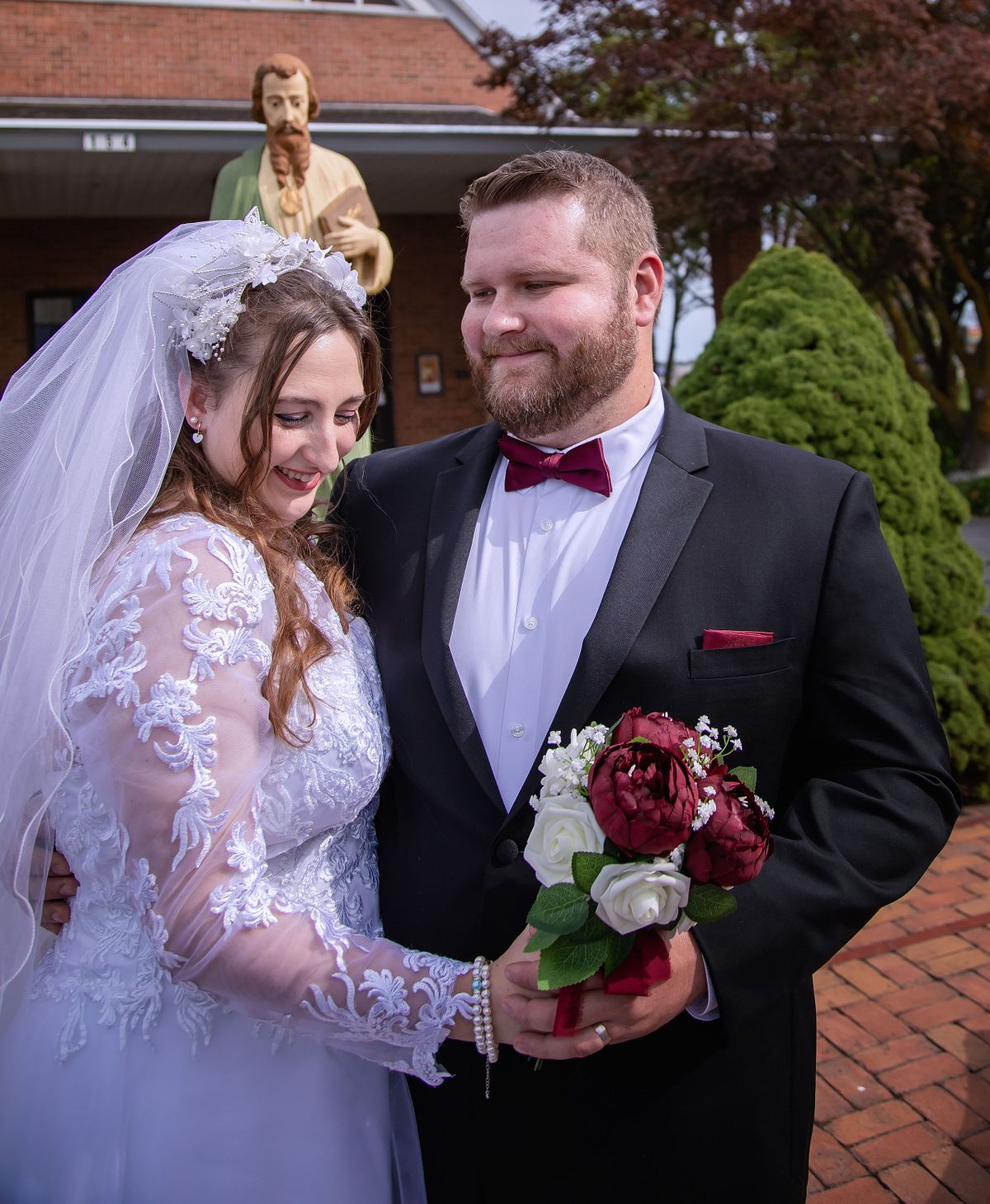 bride and groom posing in lewes, delaware, at the catholic church in front of st. lukes the apostle